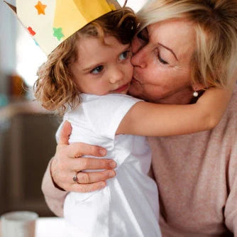 Frau küsst Kind mit Krone liebevoll auf die Wange