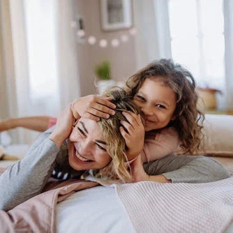 Mutter und Tochter toben gemeinsam auf dem Sofa