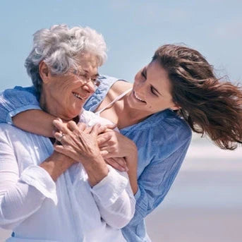 Mutter und erwachsene Tochter lächeln sich umarmend zu