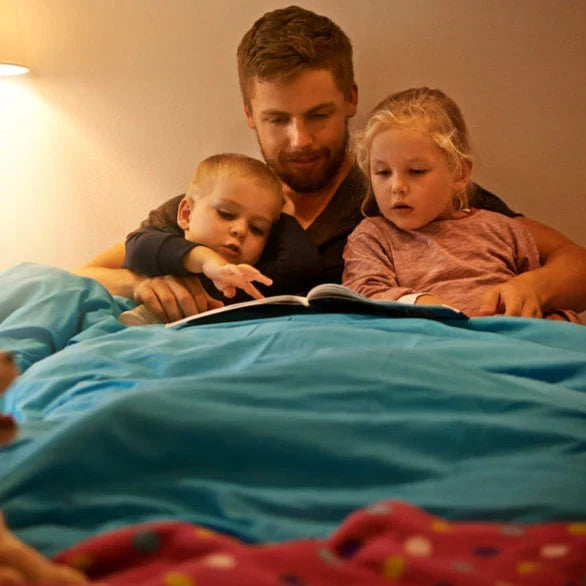 Vater liest Kindern im Bett vor