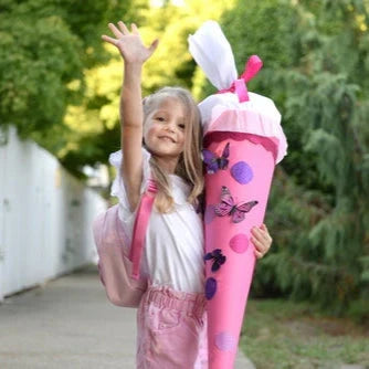 Mädchen winkt mit Schultüte in der Hand