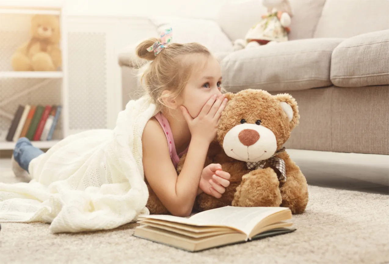 Mädchen flüstert Teddybär etwas ins Ohr