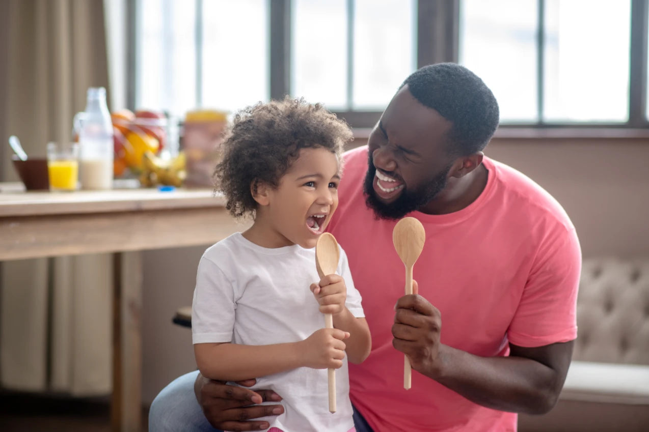 Vater und Sohn singen voller Inbrunst mit Kochlöffeln als Mikrophone