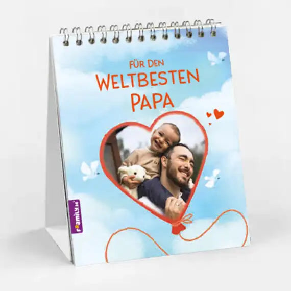 Der Tischkalender weltbester Papa von Framily ist ein spiralgebundener Tischkalender mit einem herzförmigen Foto eines lächelnden Mannes mit Kind und Stofftier, Wolken, Schmetterlingen und dem Text "Für den weltbesten Papa".