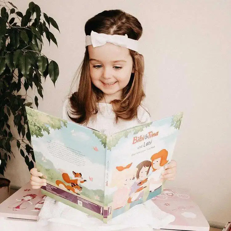 Ein Mädchen liest ein Buch von Bibi und Tina