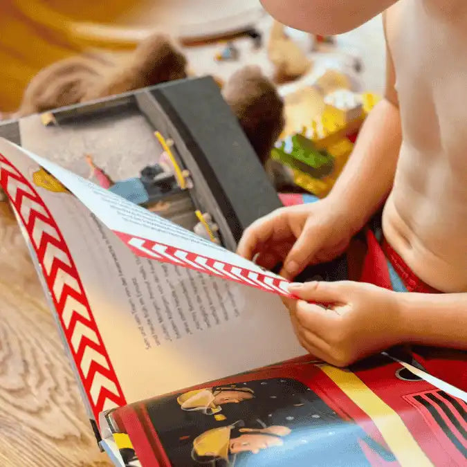 Ein Junge blättert eine Seite im Feuerwehrmann Sam Buch um