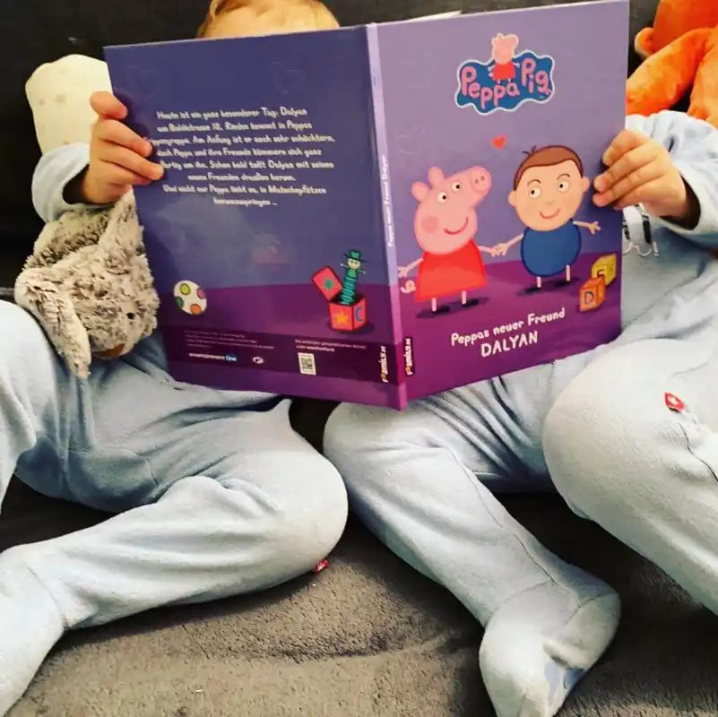 Zwei Kinder sehen sich ein personalisiertes Kinderbuch von Peppa Wutz an