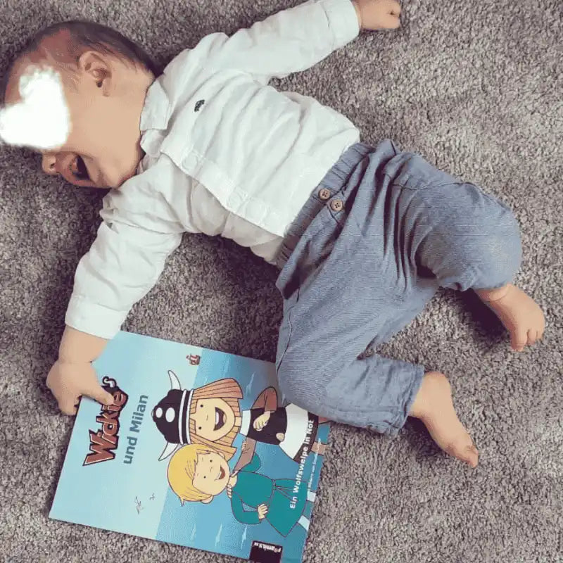 Ein Baby hält freudestrahlend ein Buch von Wickie