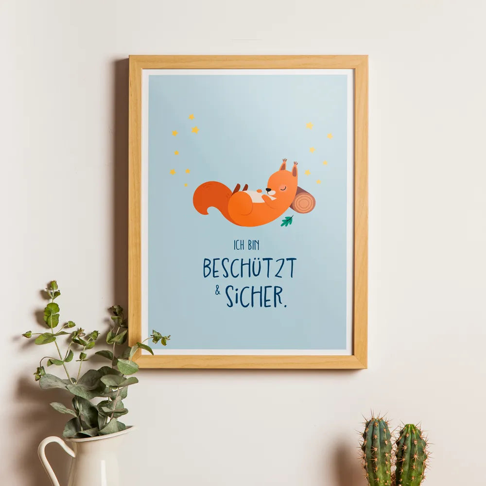 Affirmationsposter Geborgenheit hängt mit Bilderrahmen an einer Wand. Auf dem Poster schläft ein Eichhörnchen angelegt an einen Baumstamm über der Affirmation "Ich bin beschützt & sicher".