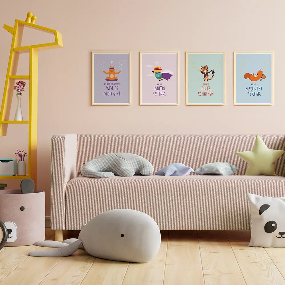 Die Affirmationsposter Mut, Geborgenheit, Selbstliebe und Selbstvertrauen hängen an einer Wand über einem Sofa in einem Kinderzimmer. Auf dem Sofa liegen verschiedene Kuscheltiere und Kissen.